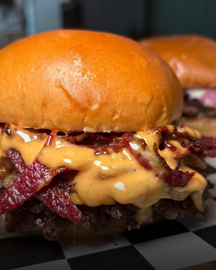 Bacon cheeseburger with cheese and burger sauce dripping over two smashed patties